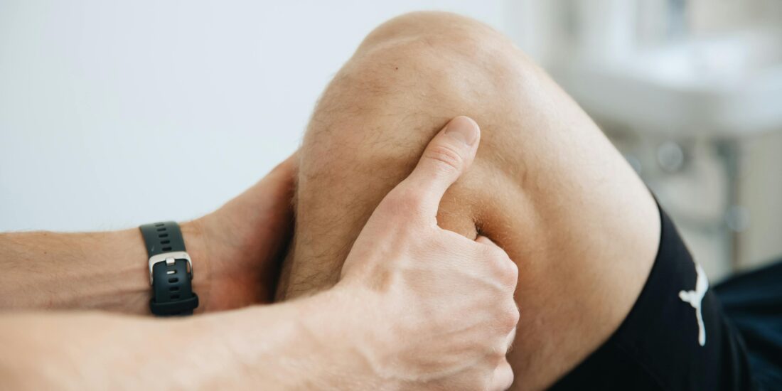A health practintioners hands performing an adjustment on a patients knee close up