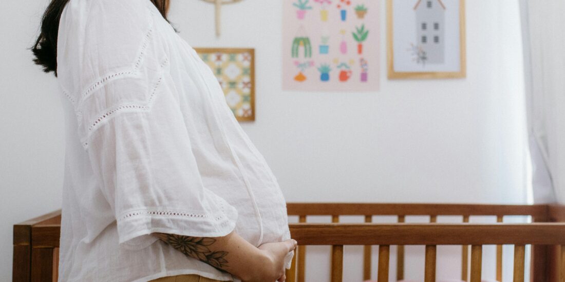 A pregnant lady holding her belly in front of their nursury