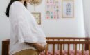 A pregnant lady holding her belly in front of their nursury