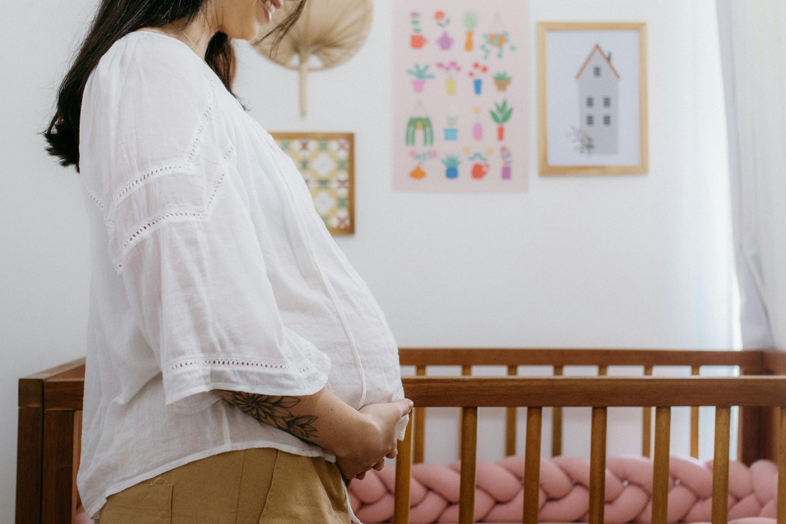 A pregnant lady holding her belly in front of their nursury