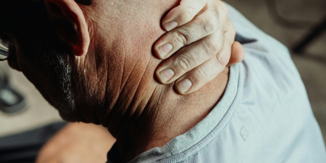 A man massaging his neck pain at his desk