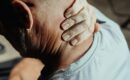A man massaging his neck pain at his desk