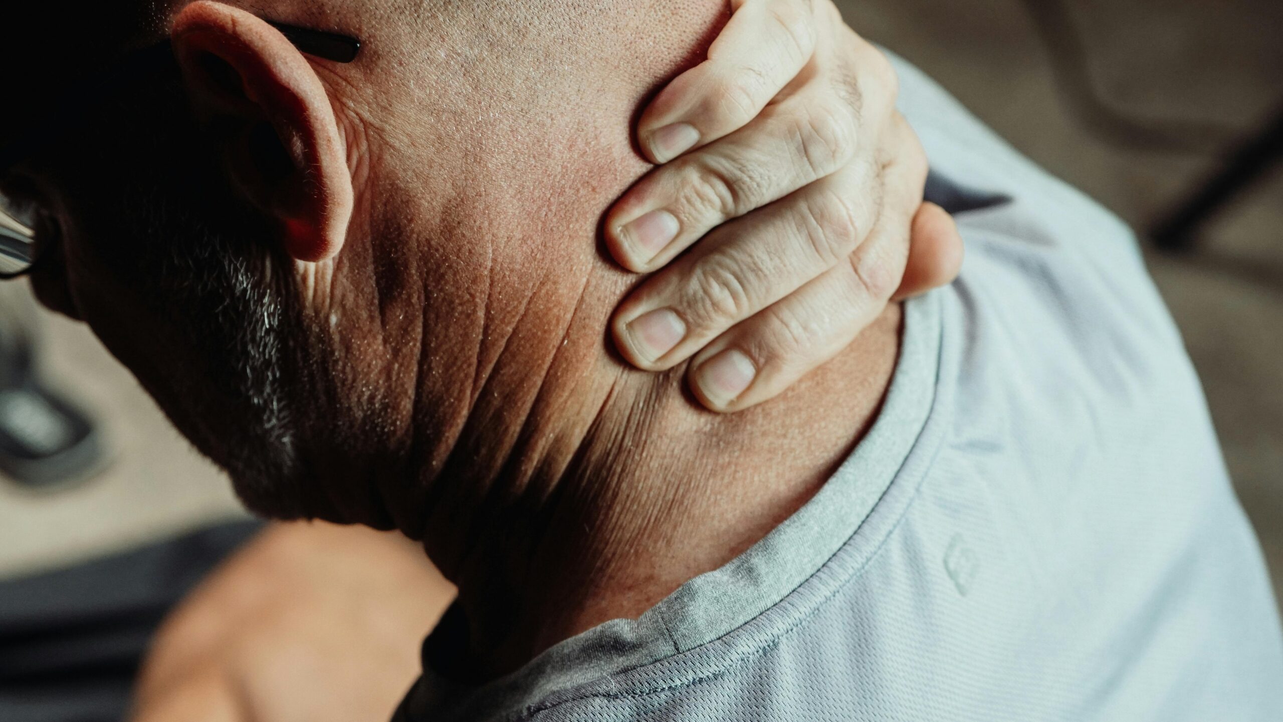 A man massaging his neck pain at his desk